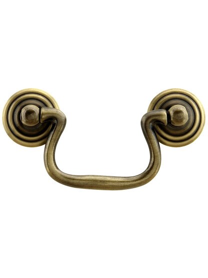 Swan-Neck Brass Bail Pull with Ringed Round Rosettes ‚Äì 2 ¬Ω‚Äù Center-to-Center in Antique Brass Finish.